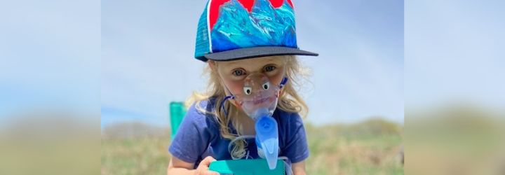 A child wearing their nebulizer on a sunny summer day.