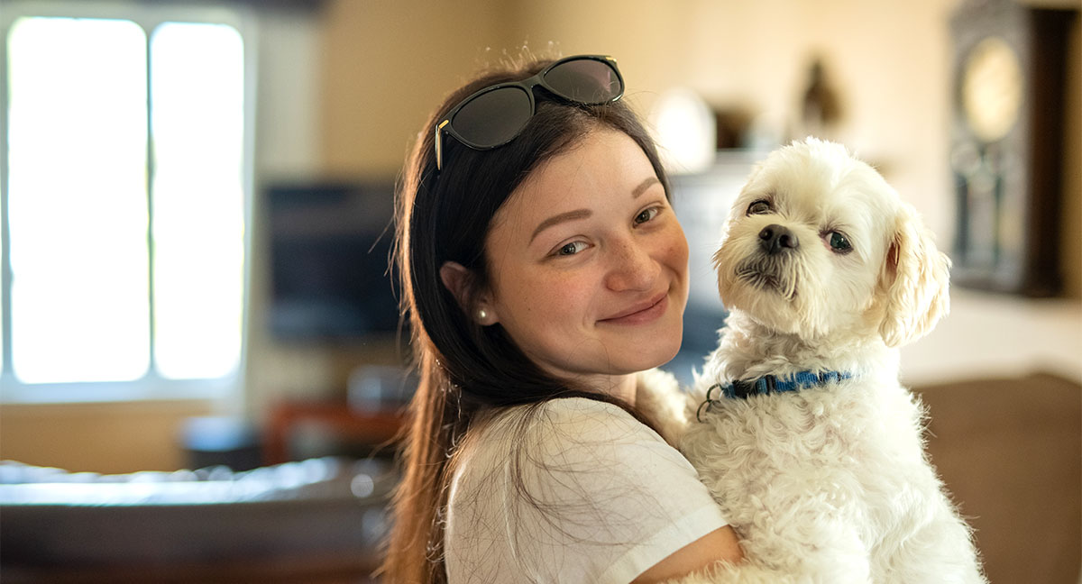 Chanelle holding her white dog, Everest, in her living room.