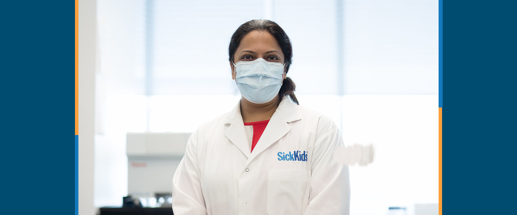 A female researcher in a lab coat looking at the camera. 