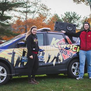 A man and woman beside a K-Rock 89.3 car and sound system