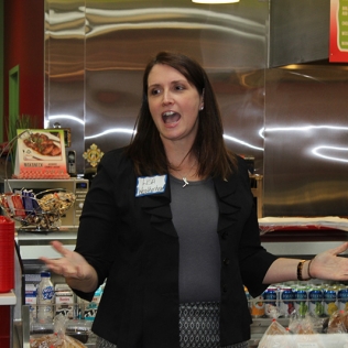 A woman saying something in front of a counter fridge
