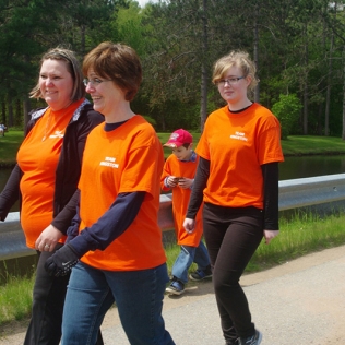 Three women in orange shirts walking