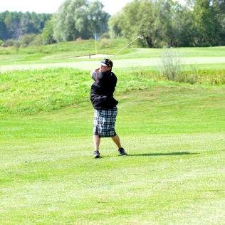 a golfer swings and watches