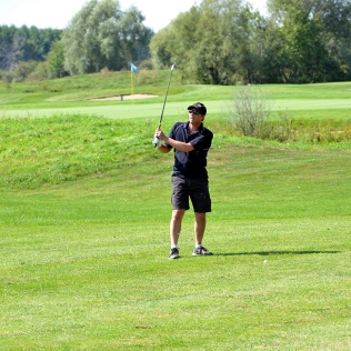 A golfer watches his shot from the fairway
