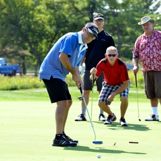 a group of golfers watching another's putt