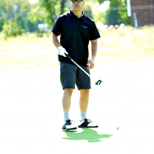 a black-clad golfer stands and watches