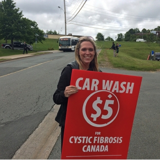 A woman holding a car wash sign