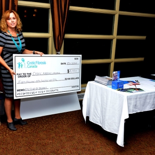 A woman holding  a cheque for $8950