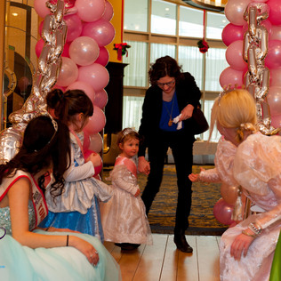 A toddler princess being helped to walk away