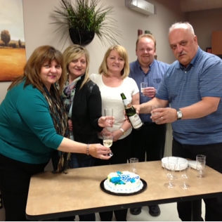 A group of people making a toast at a table with a cake
